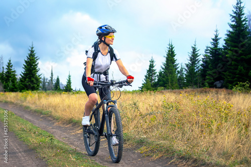Fototapeta Naklejka Na Ścianę i Meble -  beautiful and happy woman cyclist rides a bicycle on the road in nature. Healthy lifestyle and sports. Leisure and hobbies