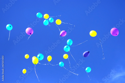 many multicolored balloons flying in the blue sky. Holiday accessories and decorations