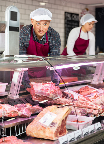 Young male butcher showing big piece of beef meat in butchery