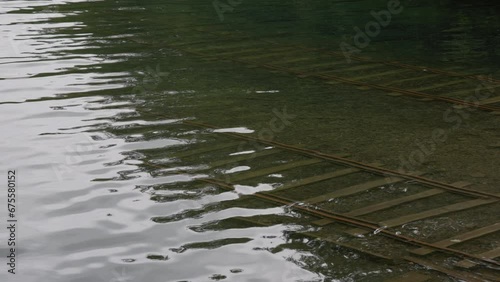 Water ripples over underwater tracks at lake boat launch in slow motion photo