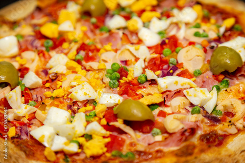 Traditional Portuguese pizza with ham, eggs, peppers, hearts of palm, tomatoes, onions, peas and cheese