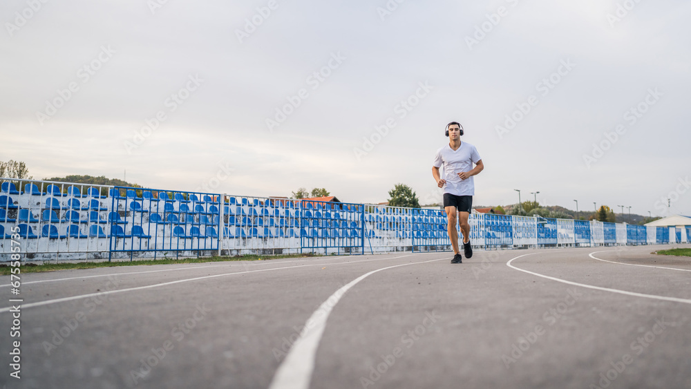 adult caucasian man jogging on the running track male athlete in stadium training run in sunny spring or summer day real people healthy lifestyle concept adult caucasian man jogging on the running track male athlete in stadium training run in sunny spring or summer day real people healthy lifestyle concept