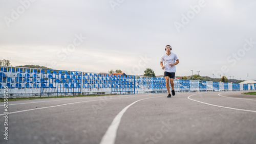 adult caucasian man jogging on the running track male athlete in stadium training run in sunny spring or summer day real people healthy lifestyle concept