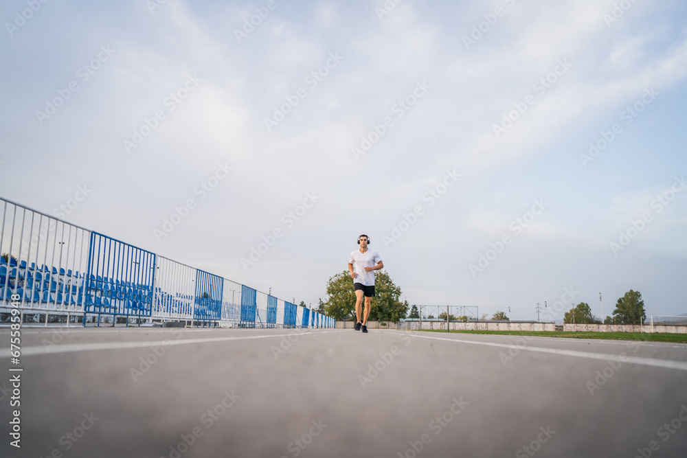 adult caucasian man jogging on the running track male athlete in stadium training run in sunny spring or summer day real people healthy lifestyle concept