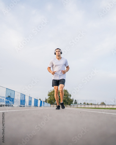Fototapeta Naklejka Na Ścianę i Meble -  adult caucasian man jogging on the running track male athlete in stadium training run in sunny spring or summer day real people healthy lifestyle concept
