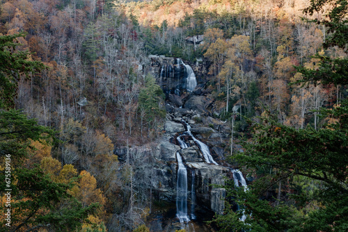 Beautiful high waterfall among the colorful autumn forest. Landscape with a mountain river and a waterfall on a sunny fall day. Whitewater Falls  South Carolina  USA