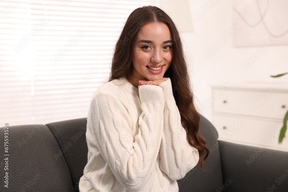 Beautiful young woman in stylish warm sweater on sofa at home Beautiful young woman in stylish warm sweater on sofa at home