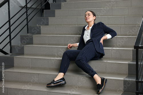 Woman fallen down stairs suffering from pain in back indoors