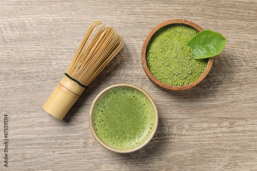 Cup of fresh matcha tea, bamboo whisk and green powder on wooden table, flat lay