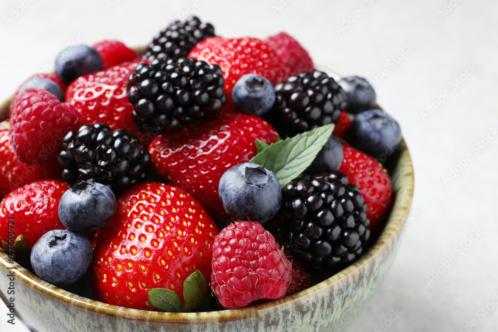 Different fresh ripe berries in bowl on table, closeup Different fresh ripe berries in bowl on table, closeup