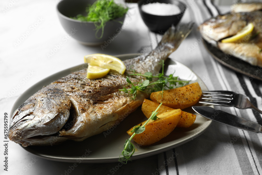 Seafood. Delicious baked fish served with lemon, potato and microgreens on light table, closeup Seafood. Delicious baked fish served with lemon, potato and microgreens on light table, closeup