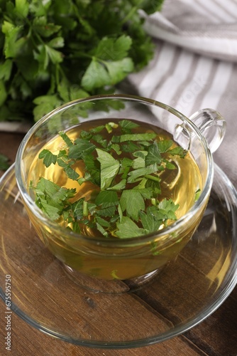 Aromatic herbal tea with parsley on wooden table, closeup
