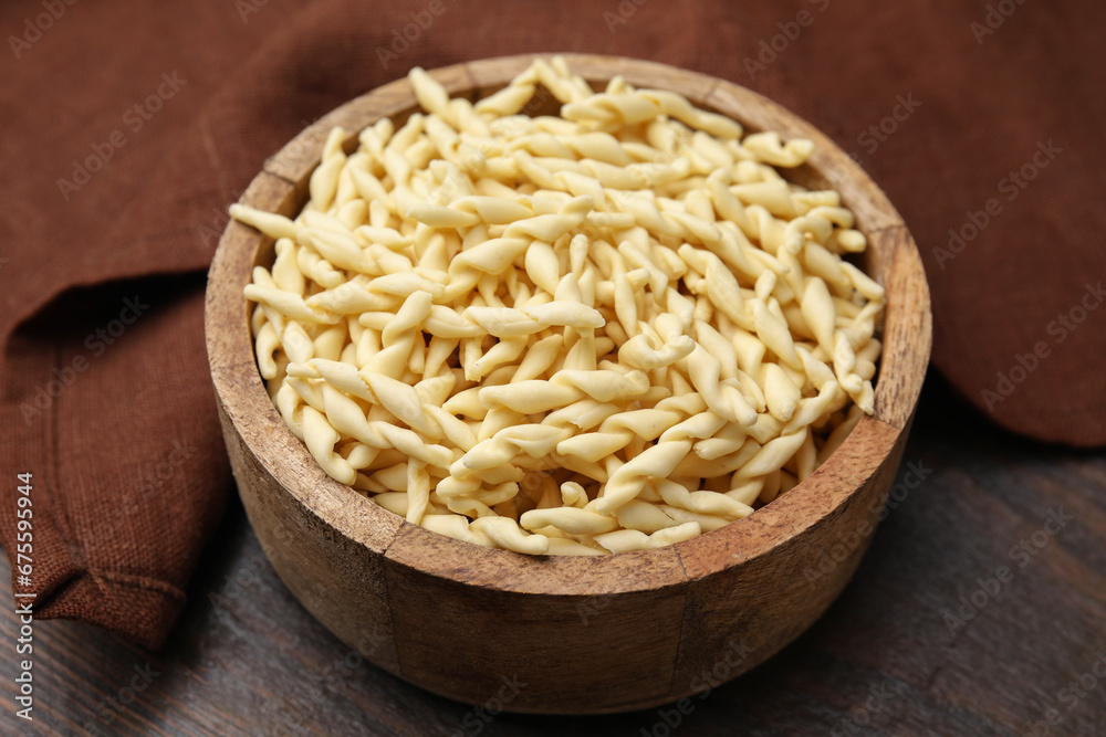 Uncooked trofie pasta in bowl on wooden table, closeup Uncooked trofie pasta in bowl on wooden table, closeup