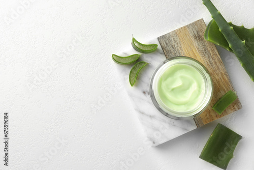 Jar with cream and cut aloe leaves on white table, flat lay. Space for text