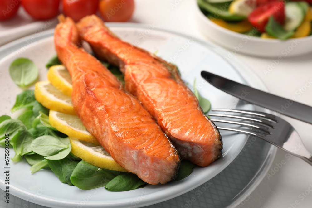Healthy meal. Pieces of grilled salmon, spinach and lemon served on white table, closeup Healthy meal. Pieces of grilled salmon, spinach and lemon served on white table, closeup