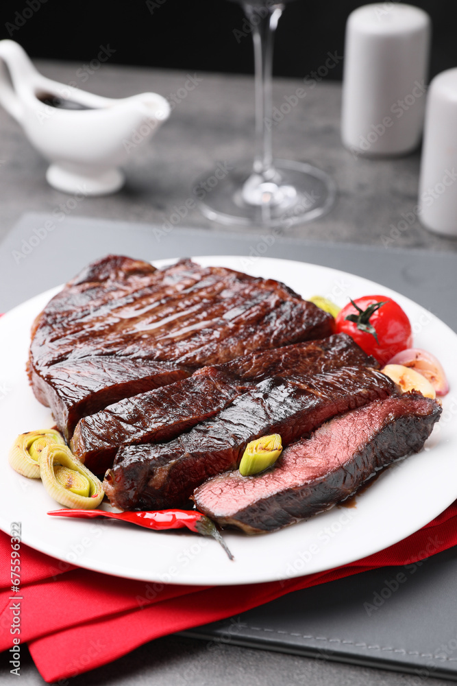 Delicious grilled beef meat served on grey table, closeup