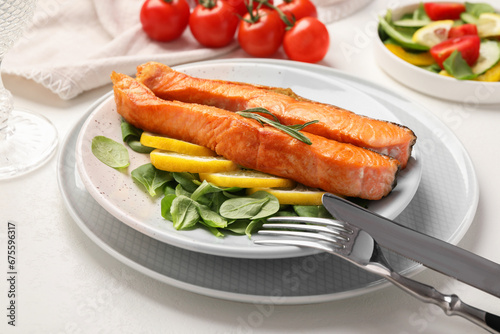 Healthy meal. Pieces of grilled salmon, spinach, lemon and rosemary served on white table, closeup