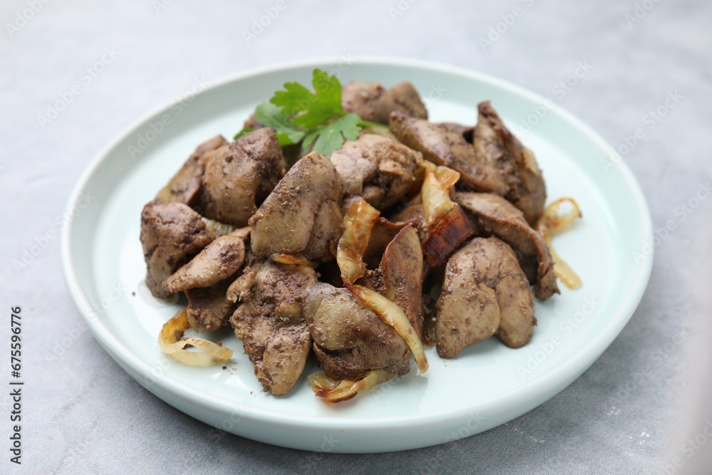Tasty fried chicken liver with onion and parsley on grey table, closeup Tasty fried chicken liver with onion and parsley on grey table, closeup