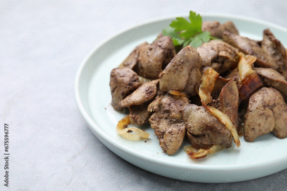 Tasty fried chicken liver with onion and parsley on grey table, closeup. Space for text Tasty fried chicken liver with onion and parsley on grey table, closeup. Space for text