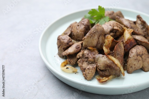 Tasty fried chicken liver with onion and parsley on grey table, closeup. Space for text