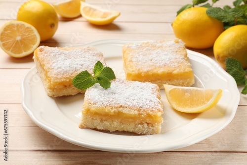 Tasty lemon bars with powdered sugar and mint on wooden table, closeup