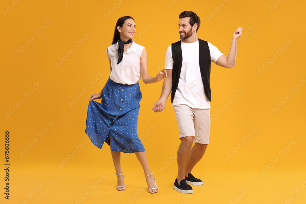 © New Africa - Happy couple dancing together on orange background