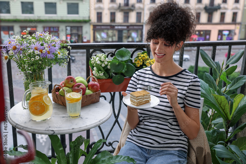 Young woman eating piece of cake on balcony with beautiful houseplants Young woman eating piece of cake on balcony with beautiful houseplants