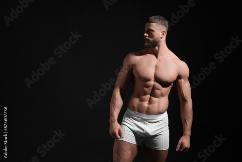 Young man in stylish white underwear on black background. Space for text © New Africa