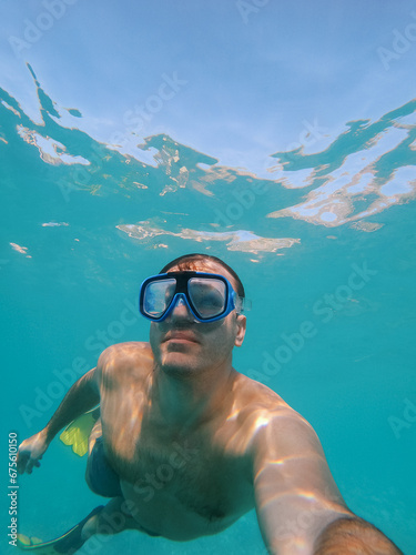 Young man in a swimming mask and fins swims underwater © Nadtochiy