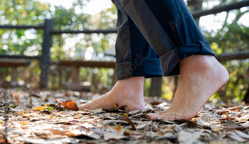 A man walking barefoot on a fallen leafy road. Healthy lifestyle concept photo