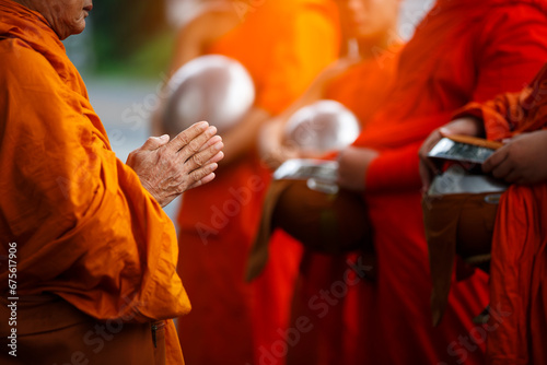 Buddhist monk holding alms bowl waitting for buddhism make merit by offering food and water at morning photo