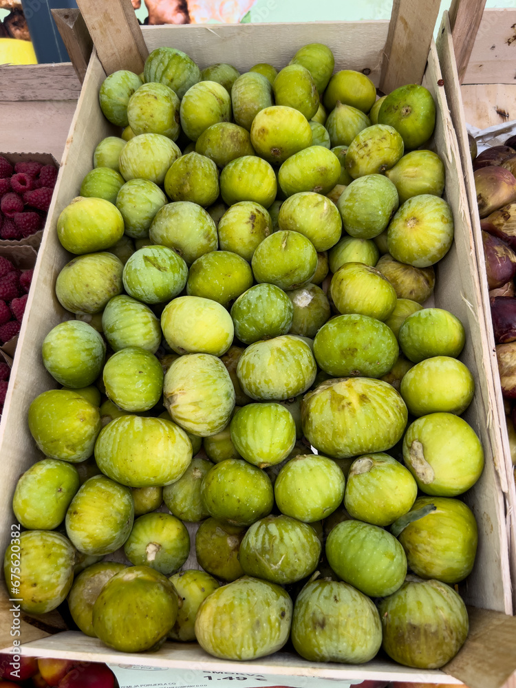Green fresh figs lie in a box on the counter