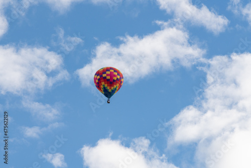 Isolated multicolor hot air balloon flying in a blue sky with white clouds at the Albuquerque International Balloon Fiesta.