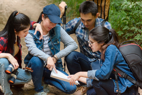 Group of friends walking on an adventure in the forest Look at the map to explore the forest and plan as a team. © 2B