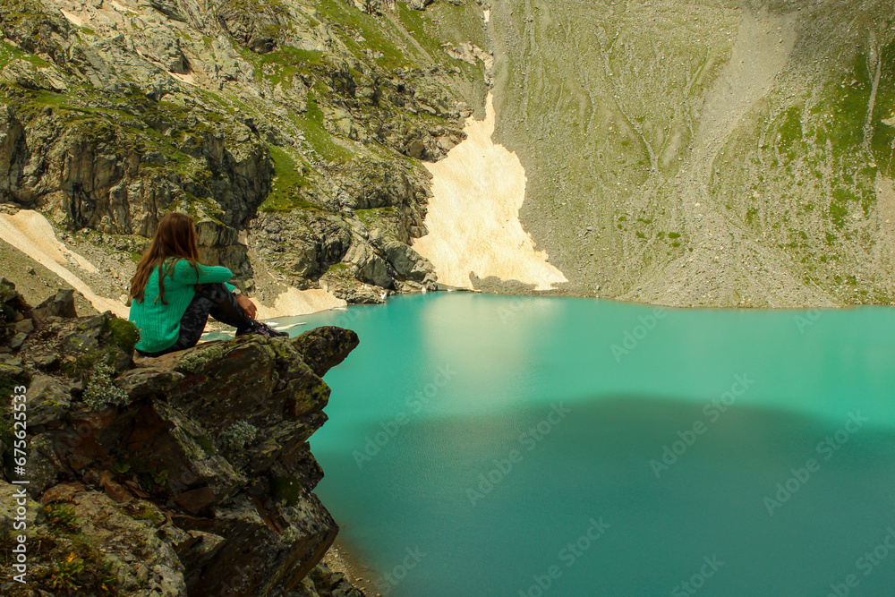 A girl sitting at the top of the mountain overlooking Sophia lakes, Arkhyz