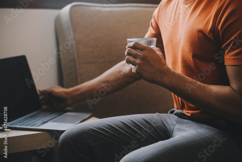 Satisfied caucasian successful guy, freelancer or ceo, relaxes at workplace with legs thrown on table. Stylish guy uses laptop, browses the Internet, looks for ideas for a project, sitting at the desk