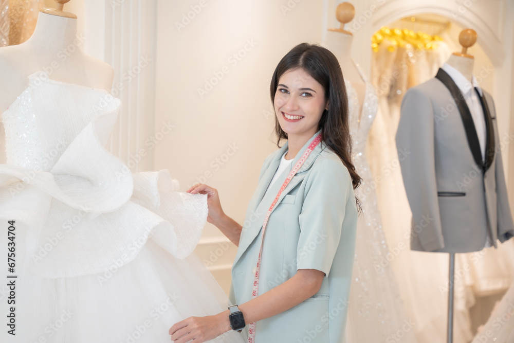 Obraz premium Beautiful female designer looking to camera with attractive smile at wedding studio.