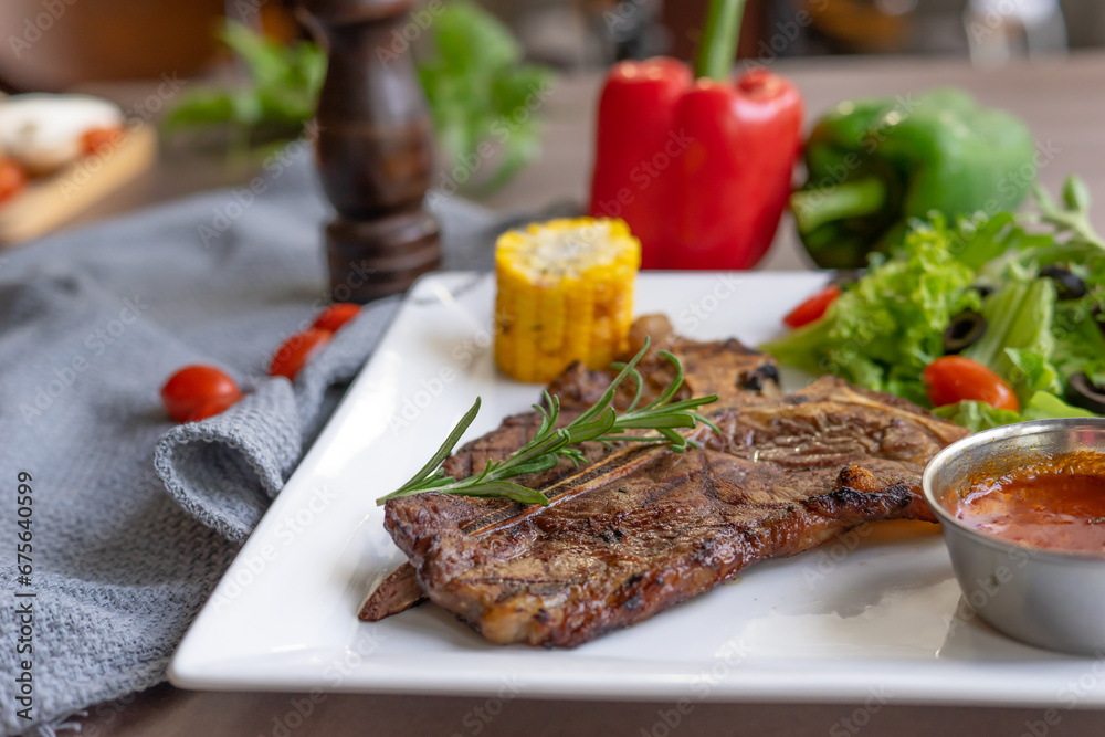 Beef steak with vegetable salad served on white plate on a wooden table