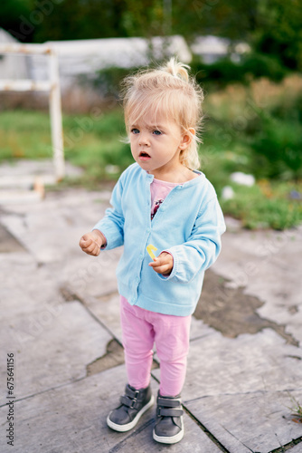 Little girl stands in the yard with her mouth open in surprise