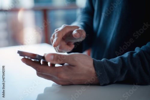 Hand of young man using smart phone social media online content, freelance worker, working online, content creator, man reading blog online on computer