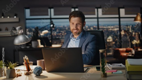 Smiling businessman taking coffee sip office night closeup. Boss looking laptop photo