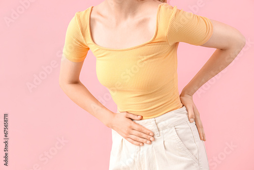 Young woman suffering from stomach ache on pink background, closeup photo