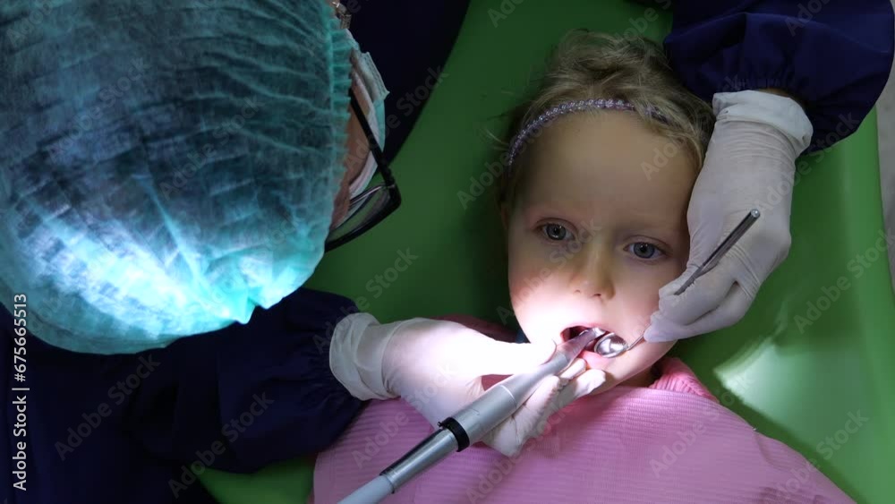 Pediatric dentist treats caries using a dental drill and dental mirror ...