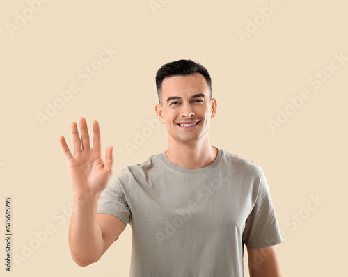 Young man waving hand on be...