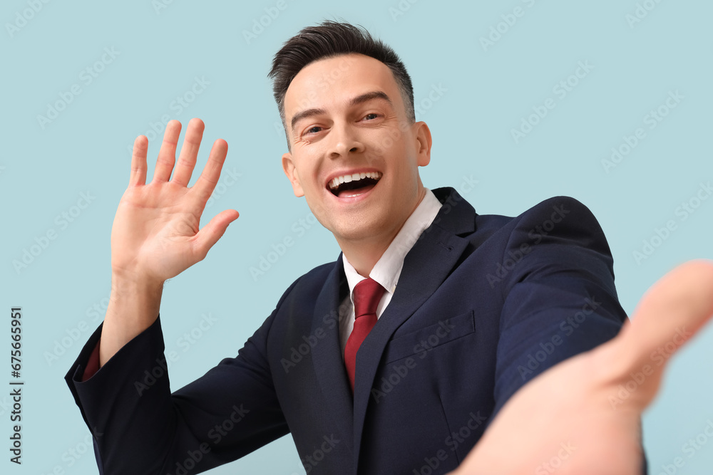 Handsome businessman waving hand on blue background, closeup Handsome businessman waving hand on blue background, closeup