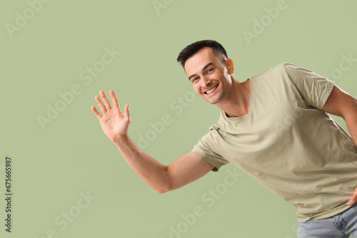 Handsome man waving hand on green background