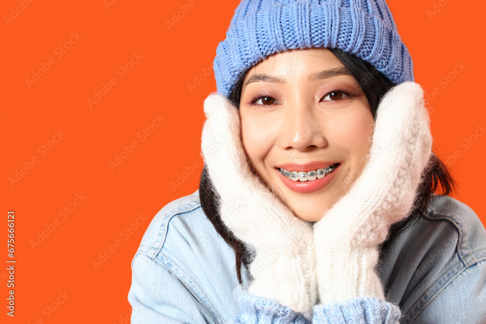 Young Asian woman in winter clothes on orange background, closeup Young Asian woman in winter clothes on orange background, closeup