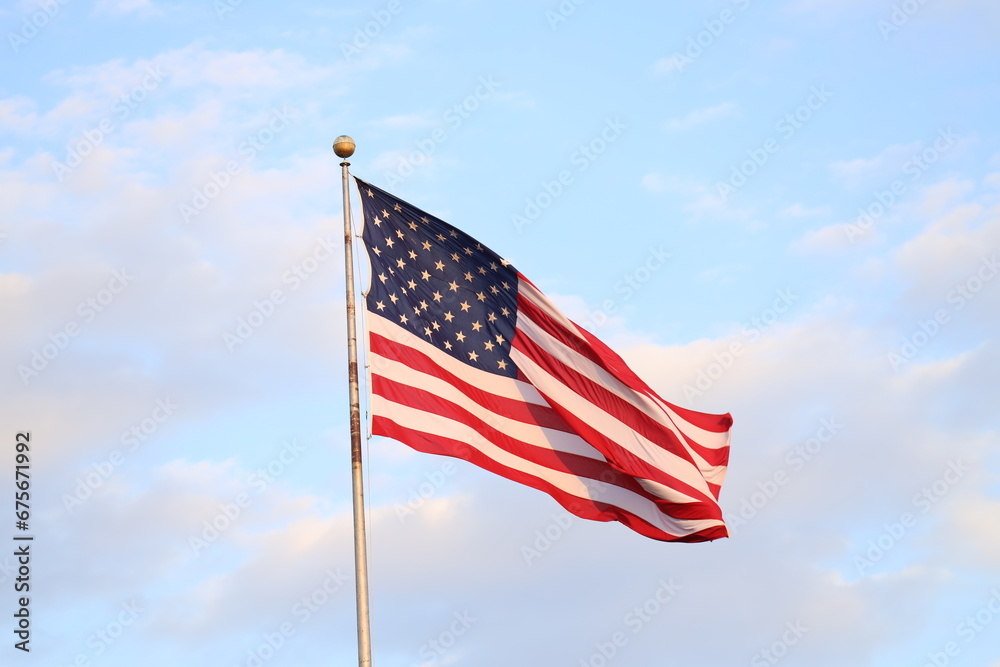 United States flag with blue sky and clouds in the background United States flag with blue sky and clouds in the background