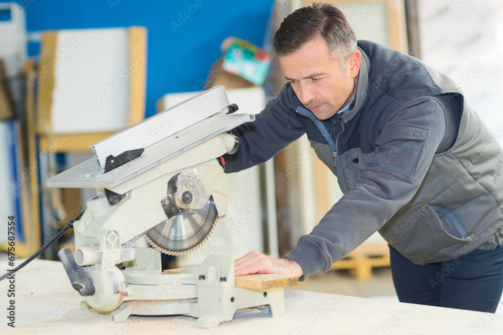 Foto cabinetry worker using drop saw to cut plank