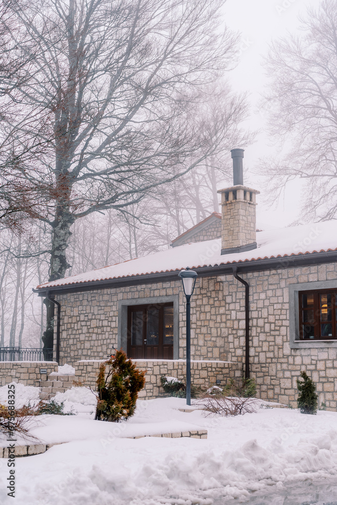 Small cozy stone house in a snowy park